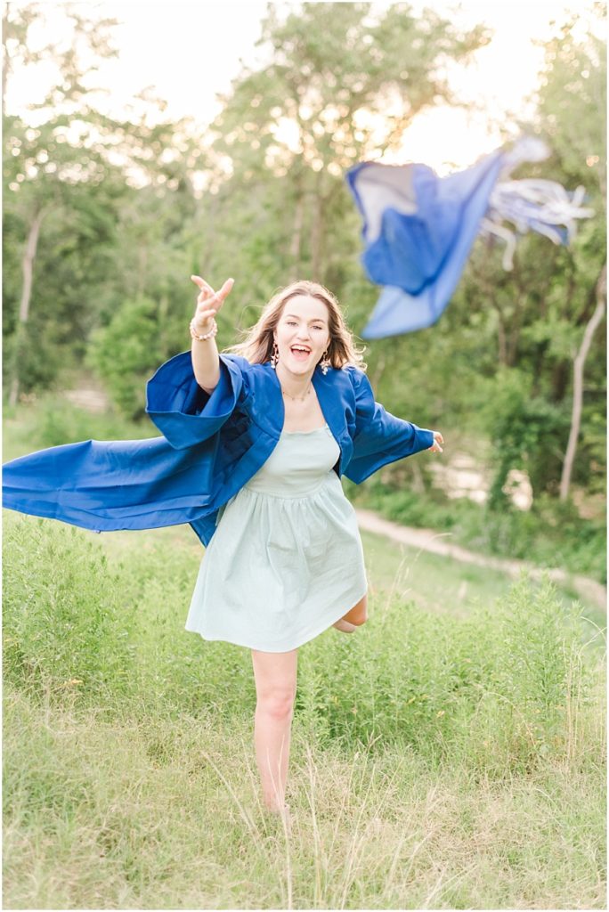 Houston senior session in the wildflowers on the Terry Hershey Trail in cap and gown throwing her cap