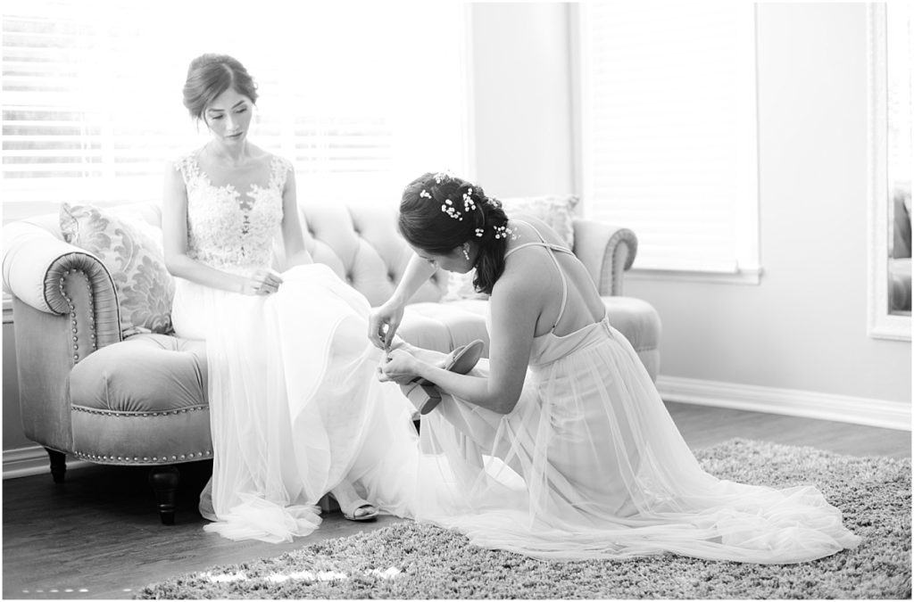 Bride putting shoes on in light and airy bridal suite