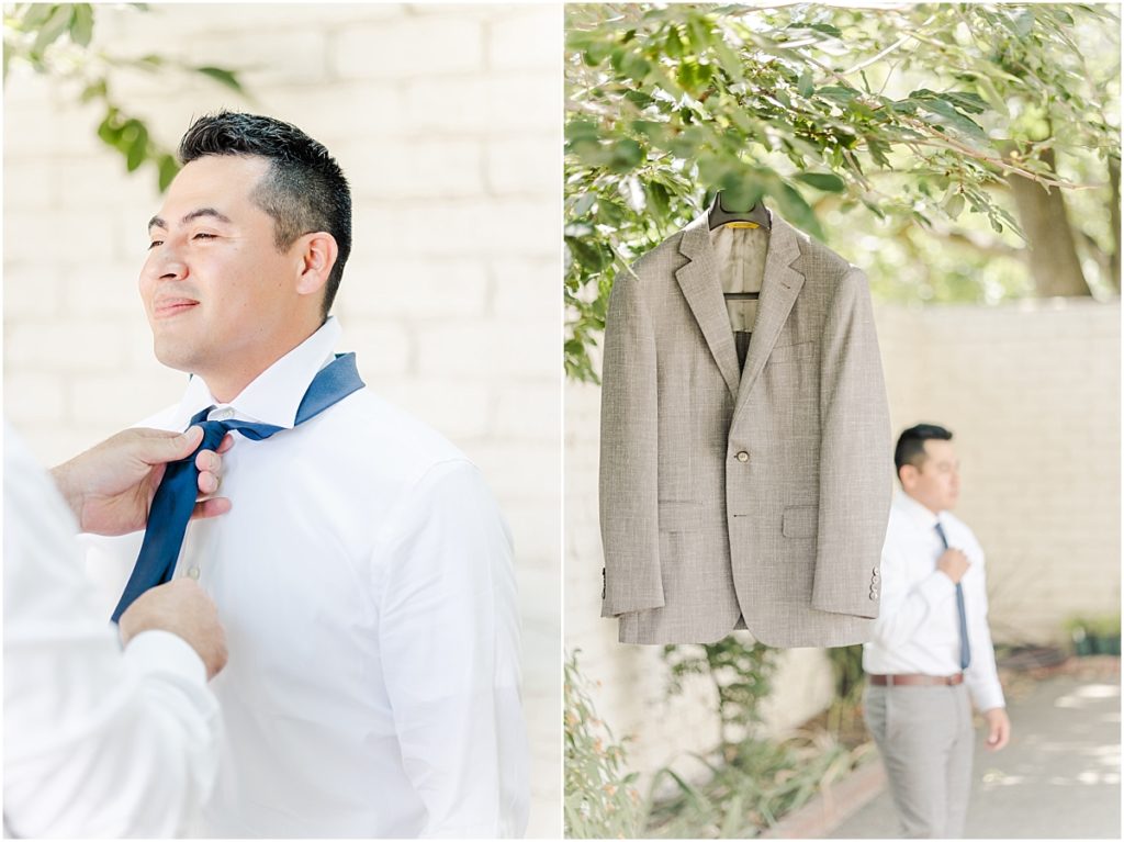 Groom getting ready outside of grooms suite with white brick wall.