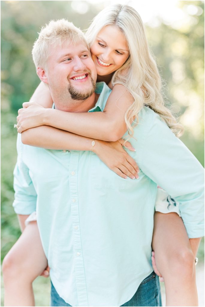 Cy-Hope Engagement Session with piggy-back rides along a dirt trail on the edge of the woods.