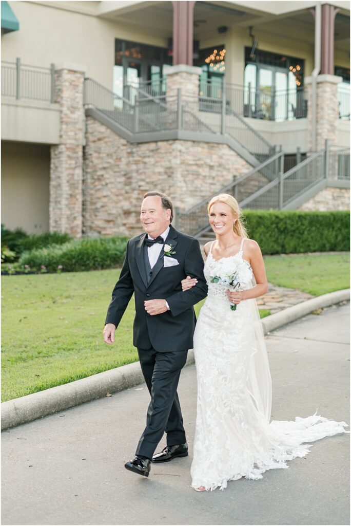 A bride and her dad walking to her wedding ceremony on a golf course in The Woodlands.
