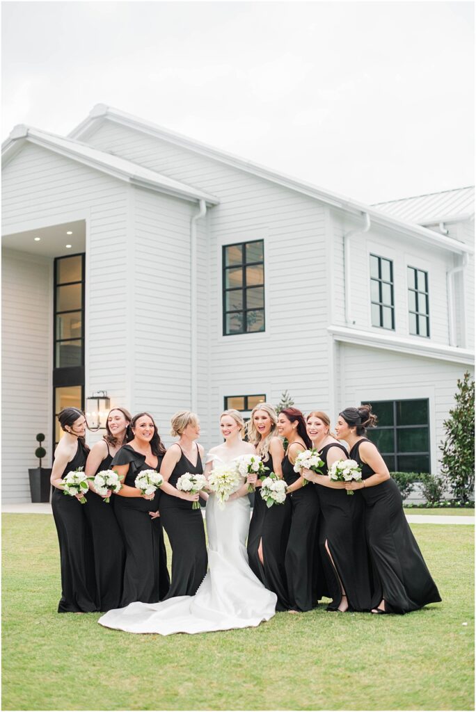 Bridesmaids in black dresses with white flowers.