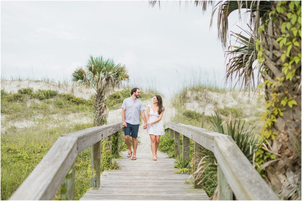 Walking on a wooden beach path in Atlantic beach at their engagement session