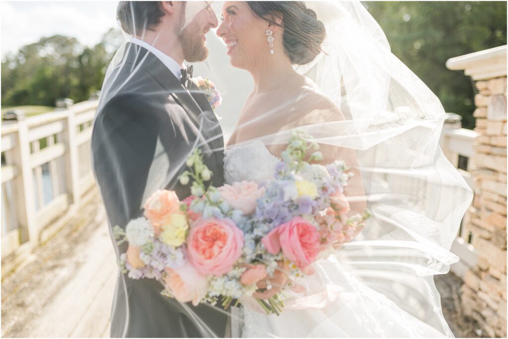 Bride and groom under the veil on the bridge on their wedding day at St. Johns Golf & Country Club